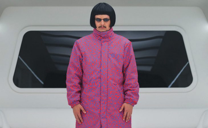 Artista Oliver Tree con traje rosa con lineas azules y lentes de sol oscuros